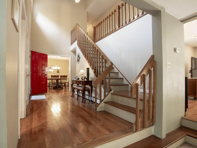 staircase with a high ceiling, an inviting chandelier, and hardwood / wood-style flooring