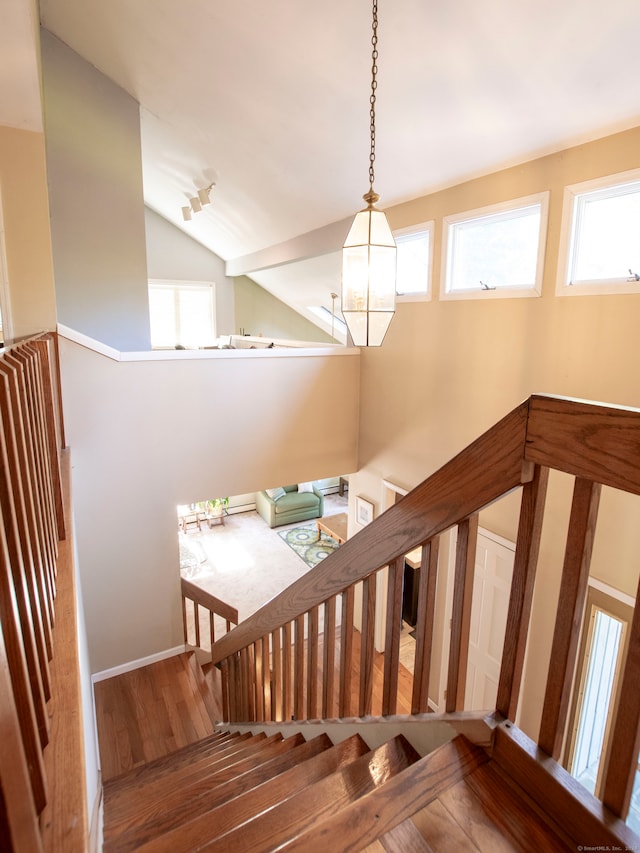 stairs with hardwood / wood-style flooring, lofted ceiling, and a chandelier