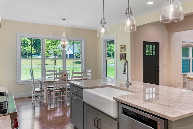 kitchen with gray cabinetry, decorative light fixtures, dark wood-type flooring, sink, and light stone counters