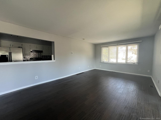 unfurnished living room with baseboards, visible vents, and dark wood-type flooring