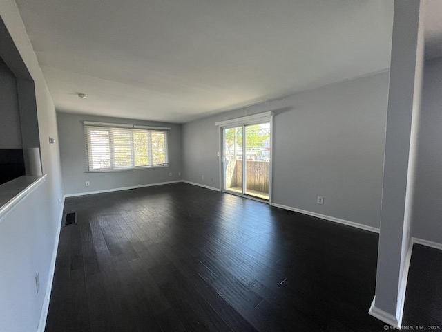 unfurnished living room featuring baseboards, dark wood finished floors, and visible vents