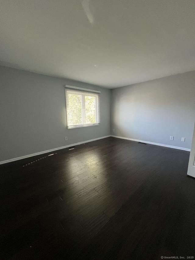 unfurnished room with baseboards and dark wood-style floors