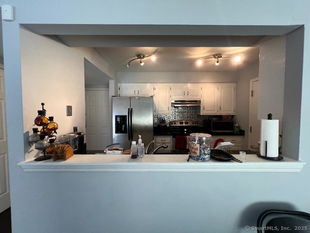 kitchen featuring backsplash, stainless steel appliances, a peninsula, and under cabinet range hood