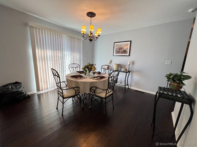 dining space featuring baseboards, visible vents, wood finished floors, and a chandelier