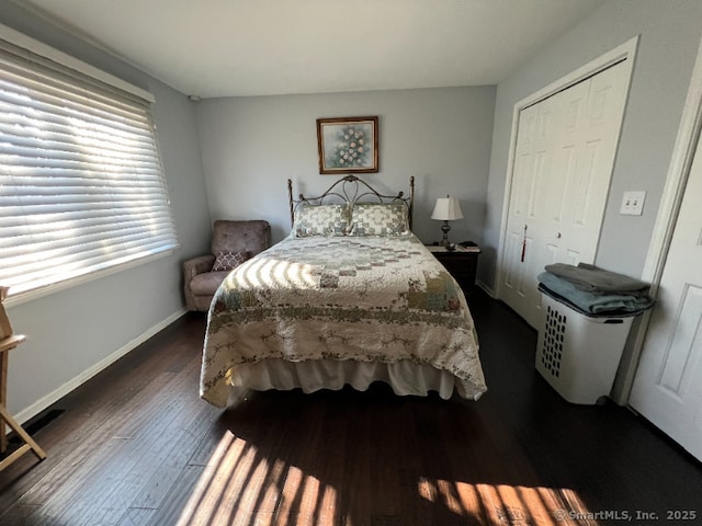 bedroom featuring a closet, dark wood finished floors, and baseboards