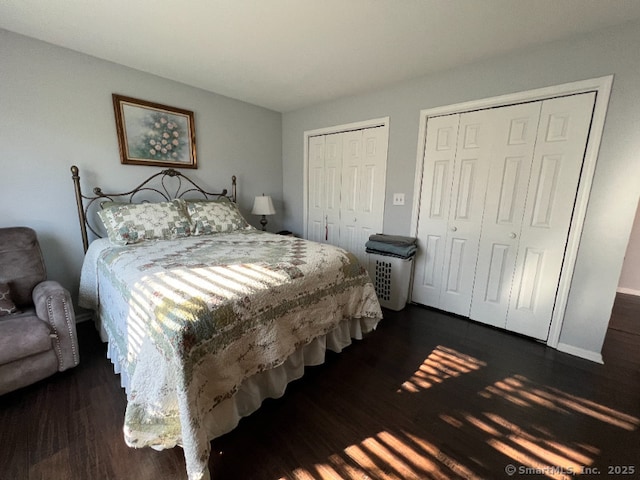 bedroom with two closets and dark wood-type flooring