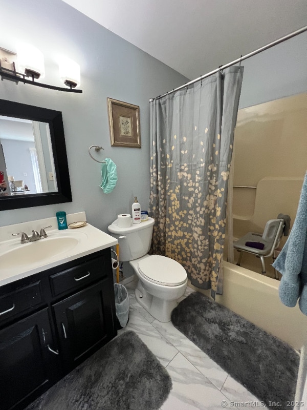 bathroom with vanity, shower / bathtub combination with curtain, toilet, and marble finish floor