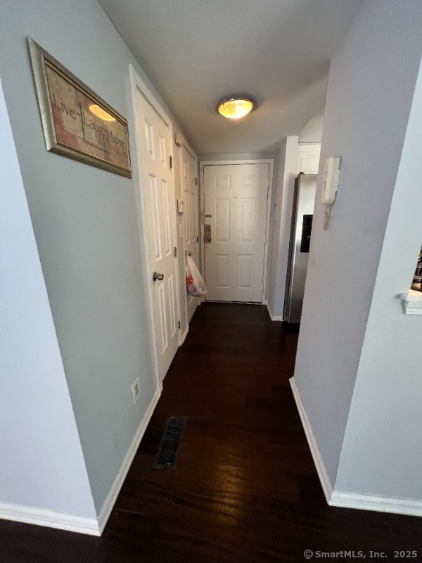hall with baseboards, dark wood-style flooring, and visible vents
