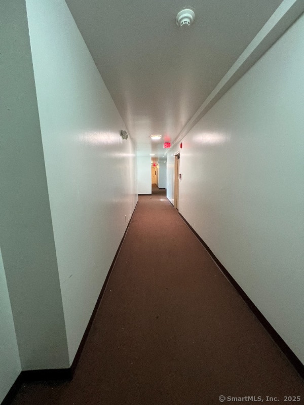 corridor with baseboards and carpet flooring