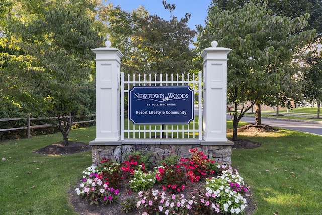 community sign with fence and a lawn