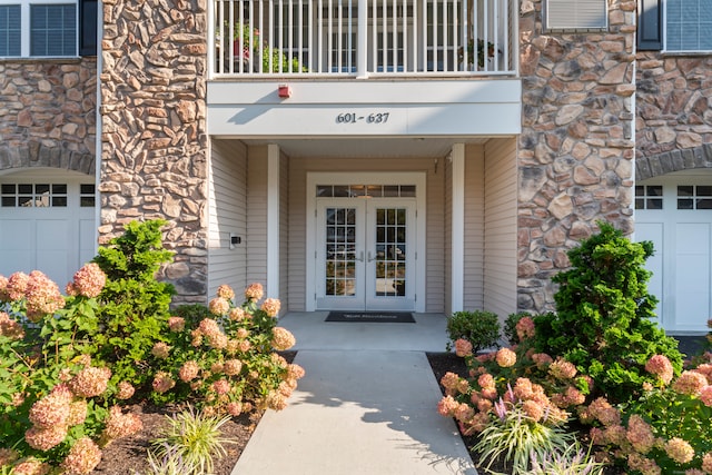 doorway to property featuring a balcony, a garage, and french doors