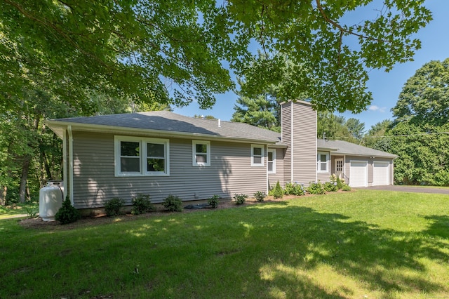 rear view of house featuring a lawn and a garage