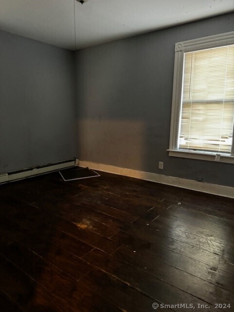 empty room with baseboard heating and dark wood-type flooring