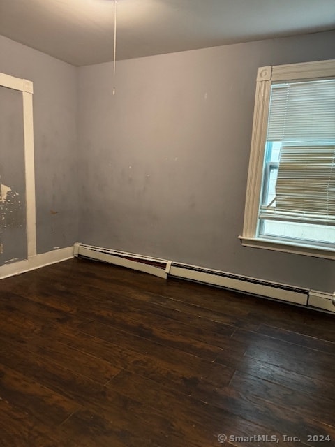 empty room with a baseboard heating unit and dark wood-type flooring