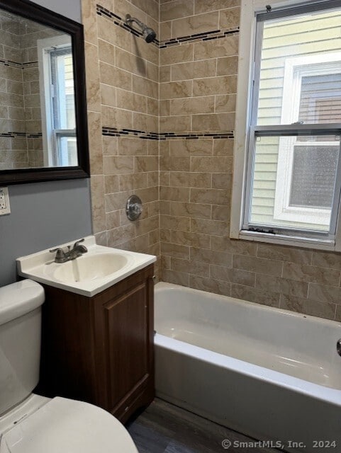 full bathroom with wood-type flooring, vanity, toilet, and tiled shower / bath