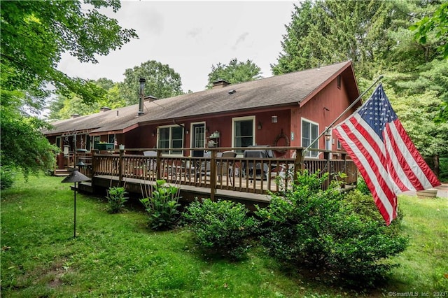 rear view of house featuring a wooden deck and a lawn