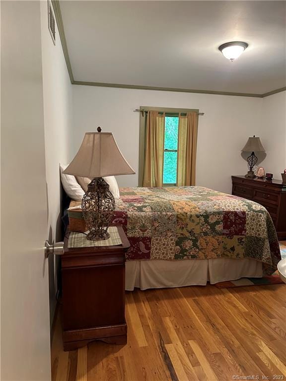 bedroom featuring crown molding and light hardwood / wood-style floors