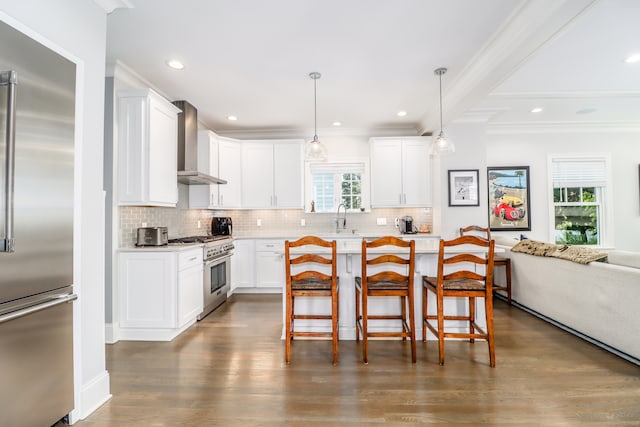 kitchen featuring a healthy amount of sunlight, white cabinetry, wall chimney range hood, and high quality appliances