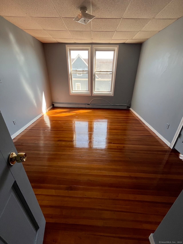 spare room featuring hardwood / wood-style floors and a drop ceiling