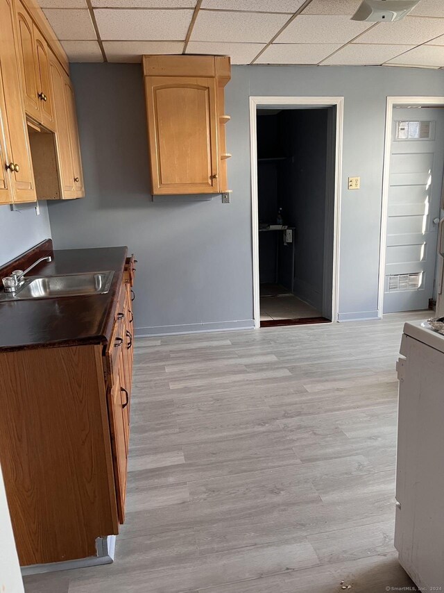 kitchen featuring light wood-type flooring, stove, a drop ceiling, and sink