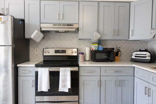 kitchen featuring gray cabinets, decorative backsplash, stainless steel appliances, and exhaust hood