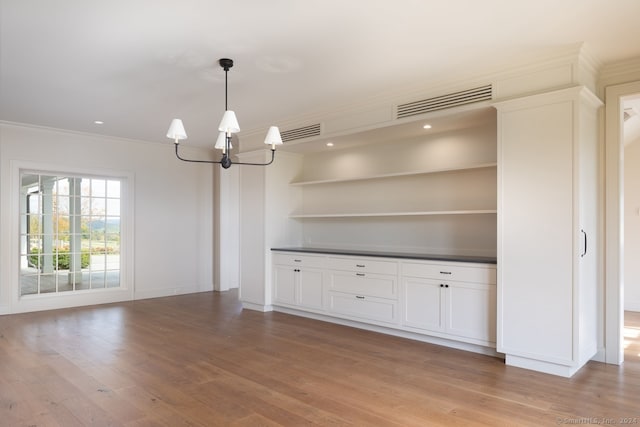 interior space with light hardwood / wood-style flooring, an inviting chandelier, and crown molding