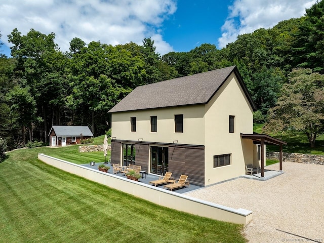 89 Under Mountain Rd, Canaan, CT 06031 - back of house with a patio, stucco siding, a yard, an outbuilding, and roof with shingles