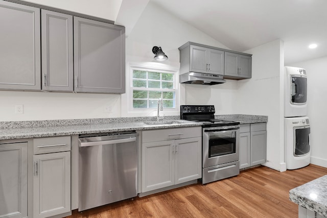 kitchen with light hardwood / wood-style floors, stacked washer / dryer, sink, lofted ceiling, and stainless steel appliances