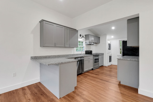 kitchen with light stone counters, stainless steel appliances, light hardwood / wood-style floors, and gray cabinetry