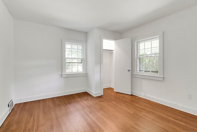 unfurnished bedroom with multiple windows, light wood-type flooring, and a closet