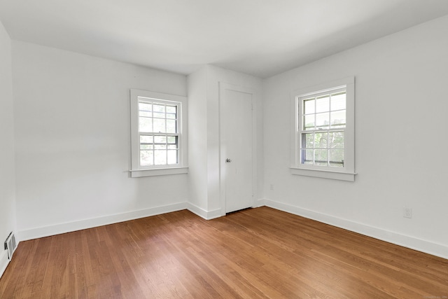 spare room featuring a wealth of natural light and hardwood / wood-style floors