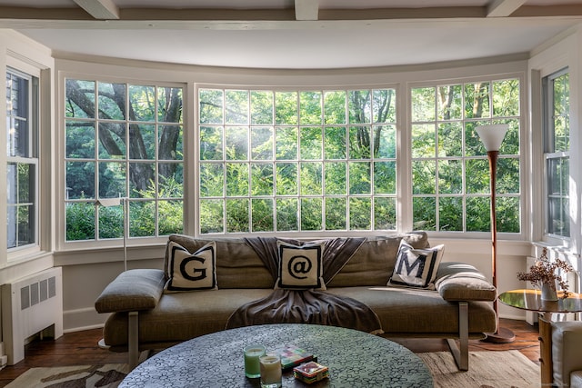 sunroom / solarium featuring radiator, beam ceiling, and a wealth of natural light