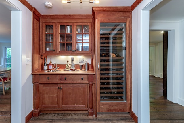 bar with dark wood-type flooring, crown molding, wine cooler, and sink