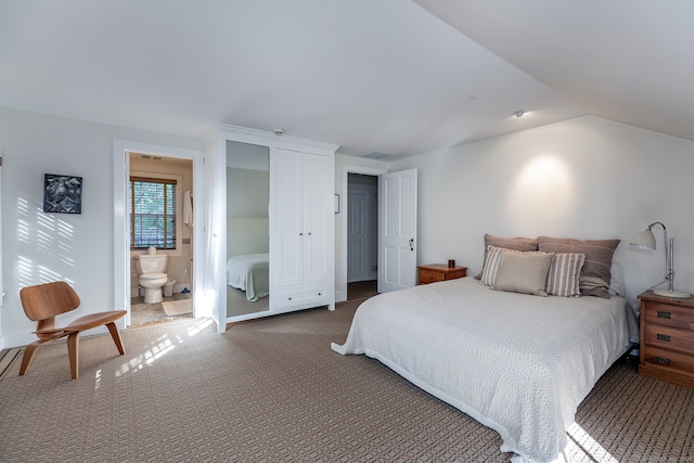 bedroom with lofted ceiling, ensuite bath, and dark carpet