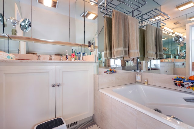 bathroom with vanity, tiled tub, and tile patterned flooring