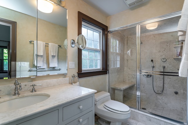 bathroom with toilet, a shower with shower door, vanity, and plenty of natural light