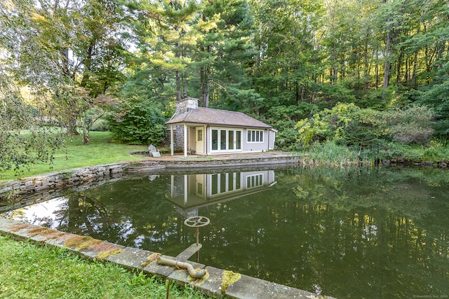 view of swimming pool with an outdoor structure, a yard, and a water view