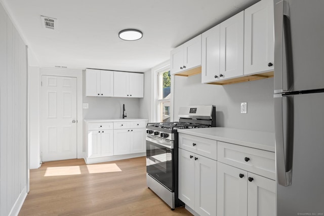 kitchen featuring stainless steel appliances, light hardwood / wood-style floors, and white cabinetry