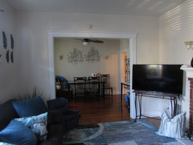 living room featuring ceiling fan and dark wood-type flooring