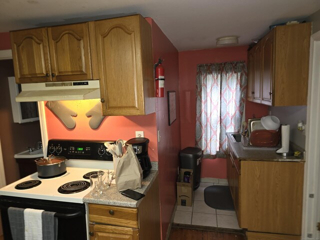 218 Oak Ave, Torrington, CT 06790 - kitchen featuring a sink, electric range, tile patterned flooring, under cabinet range hood, and light countertops