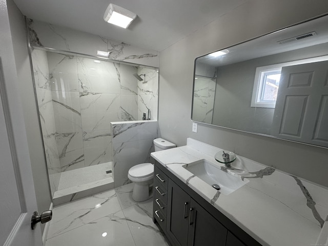 bathroom featuring a tile shower, vanity, and toilet