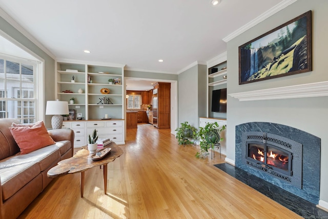 living room featuring a high end fireplace, built in shelves, a wealth of natural light, and crown molding