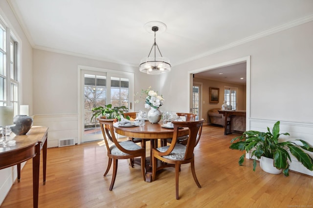 dining space featuring a wealth of natural light, light hardwood / wood-style flooring, crown molding, and an inviting chandelier