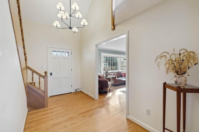 entrance foyer featuring light hardwood / wood-style flooring, high vaulted ceiling, and a chandelier