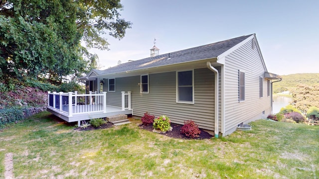 back of house with roof with shingles, a wooden deck, and a yard