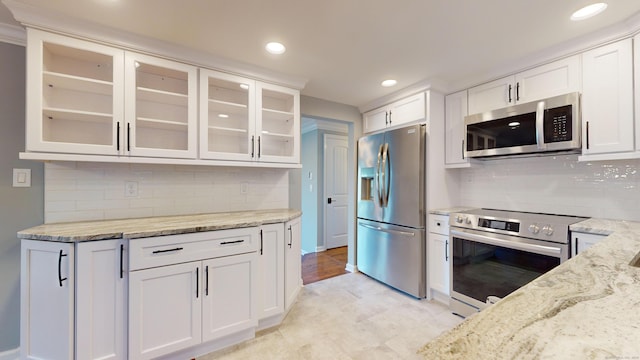 kitchen with light stone countertops, glass insert cabinets, recessed lighting, white cabinets, and stainless steel appliances