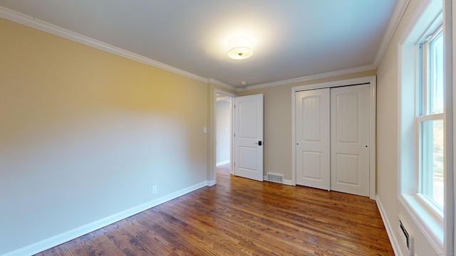 unfurnished bedroom featuring a closet, dark hardwood / wood-style flooring, and crown molding