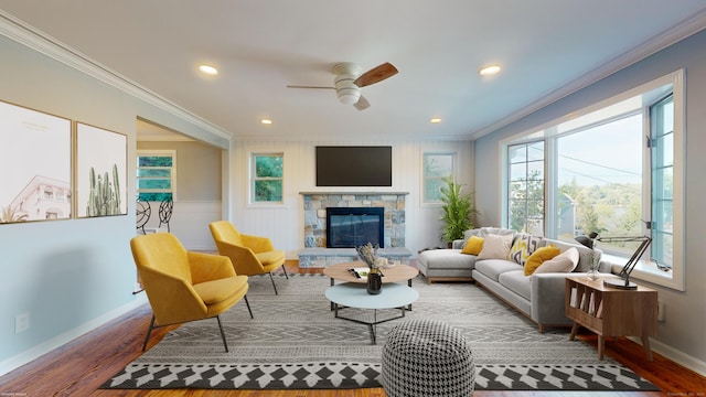 living room with hardwood / wood-style flooring, a stone fireplace, ceiling fan, and crown molding