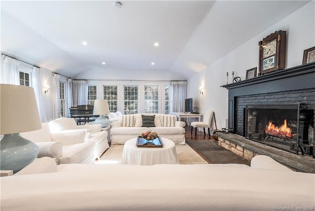 living room featuring a fireplace, vaulted ceiling, and wood-type flooring