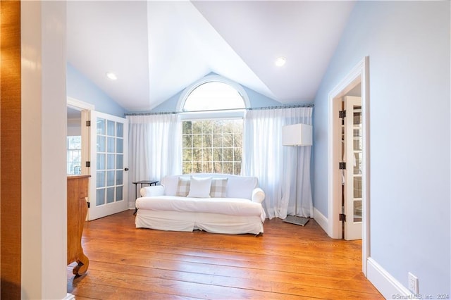 sitting room with lofted ceiling, a healthy amount of sunlight, light wood-type flooring, and french doors